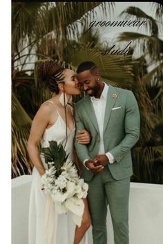 a man and woman standing next to each other in front of palm trees, kissing