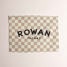 a brown and white checkered towel with rowan thomas on the front in black ink