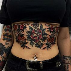 a woman has tattoos on her stomach and is wearing a black shirt with red flowers