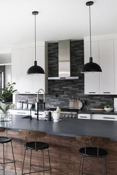 a kitchen with an island and bar stools next to the counter top that is made out of wood