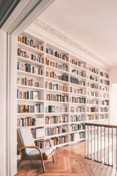 a chair sitting in front of a bookshelf filled with lots of bookcases