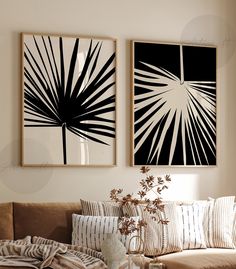 two black and white paintings hanging on the wall next to a brown couch in a living room