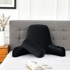 an open book is laying on a bed with a pillow in the shape of a bird