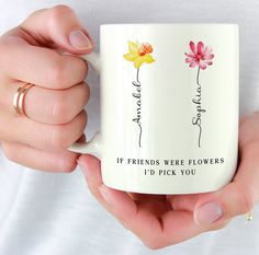 a woman holding a coffee mug with two flowers on it