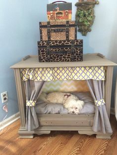 a white dog laying on top of a bed next to a dresser and suitcases