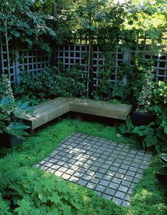 a garden with lots of green plants and some bricks in the ground, surrounded by greenery