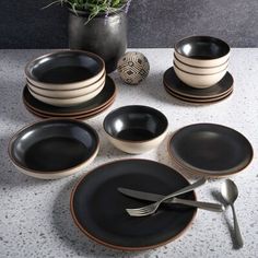 black and white dinnerware is arranged on a table with a plant in the background