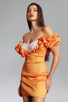 a woman in an orange dress posing with her hands on her hips and looking off to the side