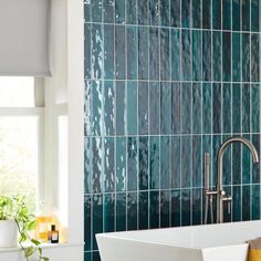 a white sink sitting under a window next to a green tiled wall in a bathroom