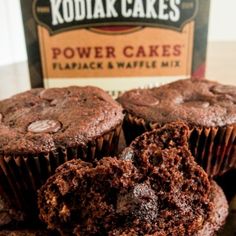 chocolate muffins sitting on top of a table next to a bottle of kodiak cakes