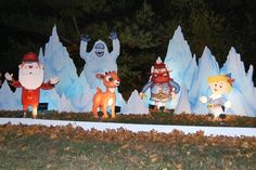 some fake snowmen and santa clause statues in front of an ice sculpture at night