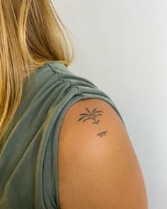 the back of a woman's shoulder with a small tattoo on her left arm