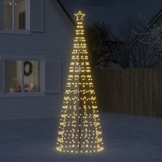 a lighted christmas tree in front of a house