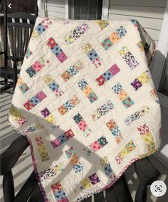 a white quilt sitting on top of a wooden chair in front of a porch door