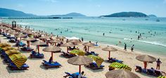 many umbrellas and chairs on the beach with people swimming in the water behind them