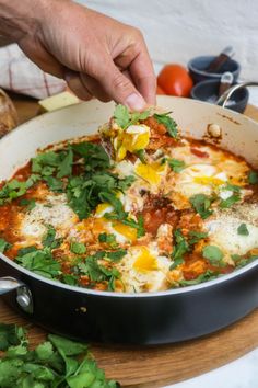 a person scooping some food out of a pan on top of a cutting board