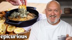 a man holding a plate with food in it next to a pan filled with bread