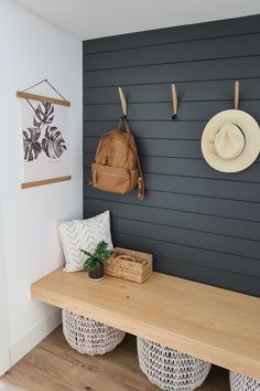 a wooden bench sitting next to a wall with two hats on it's hooks