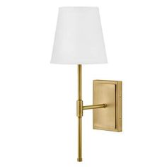 a wall light with a white shade on the side and a gold finish to it