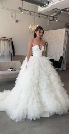 a woman in a white wedding dress standing next to a couch