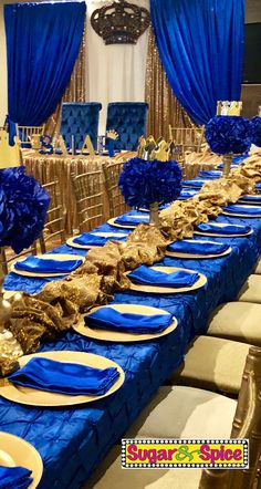 a table set up with blue and gold plates, napkins, and centerpieces