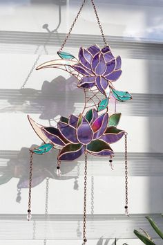 a stained glass wind chime hanging from a chain with flowers and leaves on it