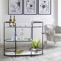 a table with wine glasses and bottles on it in front of two framed art pieces