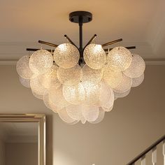 a chandelier hanging from the ceiling in a room with white walls and stairs