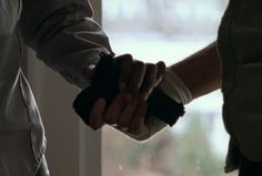 two people shaking hands in front of a window