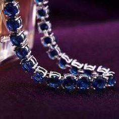 A classic tennis bracelet with a colorful surprise. 28 of the highest quality Sapphire Blue Swiss CZ diamonds in a solitaire pattern. The setting is triple platinum clad (highest quality platinum plating) and each stone is prong-set for security. Snap hook closure for comfort and security. Flexible for comfort--can be worn all day! Swiss CZs are known for their sparkling reflection of light with deep colors. Very versatile can be worn every day or for a special occasion. Coordinates well with yo Sapphire Cubic Zirconia Tennis Bracelet With Gemstone, Crystal Round Tennis Bracelet For Party, Crystal Tennis Bracelet For Parties, Sapphire Cubic Zirconia Tennis Bracelet, Blue Brilliant Cut Tennis Bracelet For Gift, Blue Brilliant Cut Tennis Bracelet Gift, Silver Sapphire Tennis Bracelet, Silver Party Tennis Bracelet With Prong Setting, Blue Cubic Zirconia Bracelets For Party