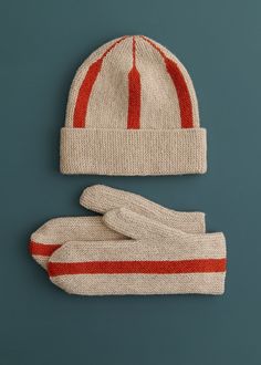 a knitted hat and mittens sitting on top of a blue surface with red stripes