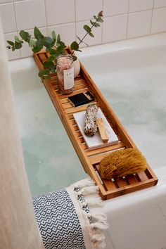 a bath tub with two trays on the side holding candles and other items in it