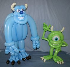 two inflatable monsters are standing next to each other, one is green and the other is blue