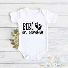 a baby bodysuit with the words bebe en camino written in spanish on it