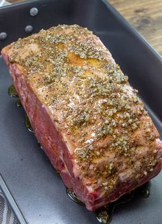 a piece of meat sitting on top of a pan covered in green sauce and seasoning