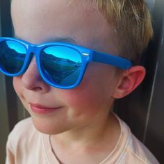 Elevate your child's style with our Blue Kids Ray-Ban Sunglasses. These iconic shades feature a sleek blue frame, reminiscent of the classic Ray-Ban design. Designed to provide both fashion and functionality, these sunglasses offer UV protection while adding a touch of cool sophistication to any outfit. Let your little one shine with confidence and timeless style, as they rock these must-have blue Ray-Ban sunglasses. Blue Fun Sunglasses With Tinted Lenses, Blue Tinted Fun Sunglasses, Fun Blue Tinted Sunglasses, Blue Wayfarer Sunglasses With Mirrored Lenses, Blue Plastic Sunglasses With Mirrored Lenses, Blue Plastic Sunglasses With Uva Protection, Fun Blue Sunglasses For The Beach, Blue Mirrored Plastic Sunglasses, Fun Blue Polarized Sunglasses