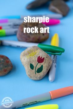 some rocks and markers on a blue surface with the words sharpie rock art written above them