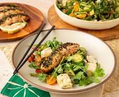 a white plate topped with fish next to a salad