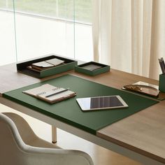 a table with a tablet, pen and notebook on it in front of a window