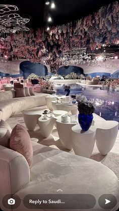 a room filled with lots of white couches and tables covered in pink and blue pillows