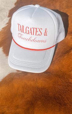 Get ready for game day with the "Tailgates & Touchdowns" trucker hat--a must-have for every fan. Designed with breathable mesh and a comfortable snapback fit, this hat is perfect for long days at the tailgate and cheering in the stands. The bold lettering on the front lets everyone know your priorities: great times and great football. Whether you're rooting for your favorite team or just soaking up the atmosphere, this trucker hat is the ultimate accessory for any football enthusiast. White Trucker Baseball Cap For Fan Gear, White Trucker Baseball Cap For Fans, Team Spirit Trucker Hat Snapback, White Trucker Hat For Game Day, Trucker Style Adjustable Snapback Hat For Game Day, Adjustable Trucker Snapback Hat For Game Day, Adjustable Trucker Snapback For Game Day, Game Day White Trucker Baseball Cap, White Trucker Baseball Cap For Game Day