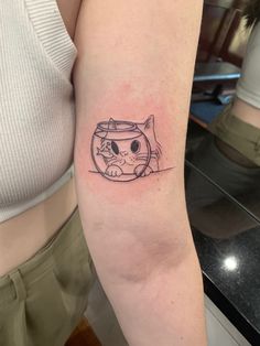 a woman's arm with a tattoo of a cat in a fish bowl on it