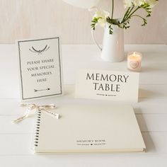 a table with a book, candle and flowers on it next to a card that says memory table