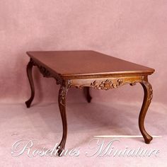 a small wooden table sitting on top of a white floor next to a pink wall