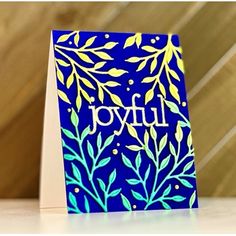 a card with the word joy on it sitting on a table next to a vase