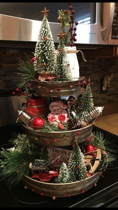 three tiered trays with christmas trees and ornaments in them on top of a stove