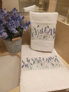 towels and flowers are sitting on the edge of a bathtub next to a flower pot