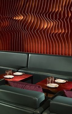 two tables with place settings in front of a wavy wall