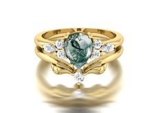 a gold ring with a green and white stone in the center, surrounded by diamonds