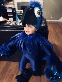 a little boy in a blue costume sitting on the floor